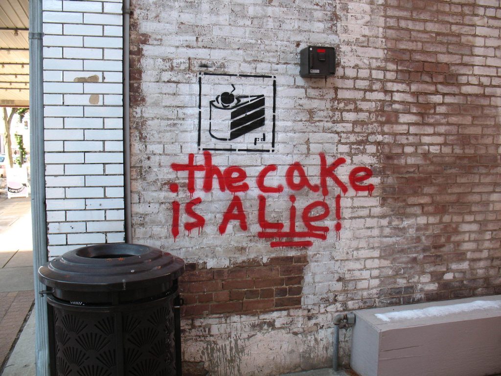 A building wall with a portal game cake graphic with "the cake is a lie" written underneath